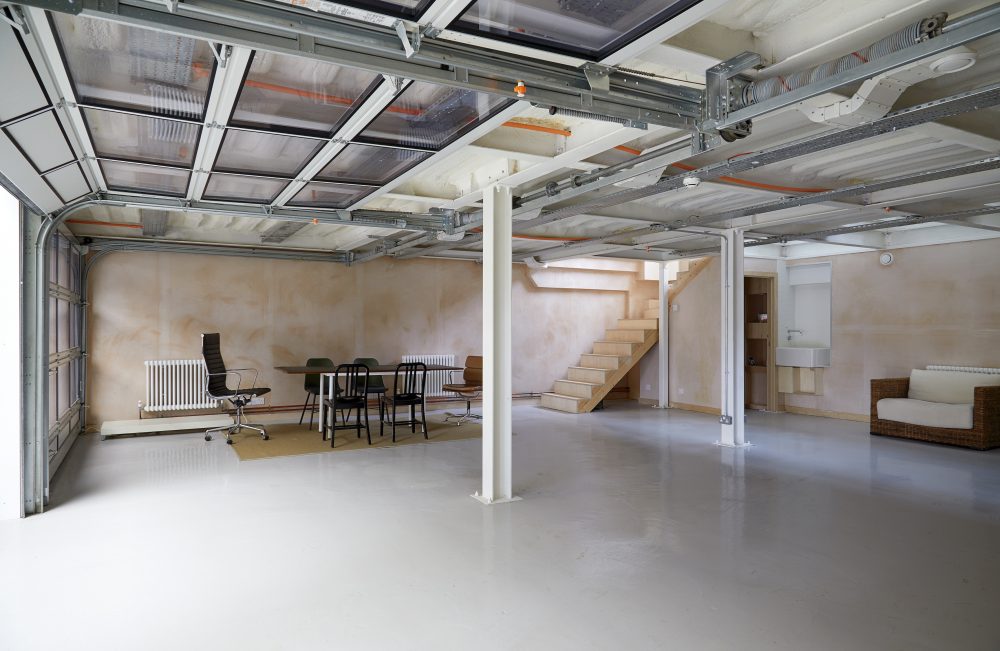 Ground floor garage with staircase to studio and sectional doors